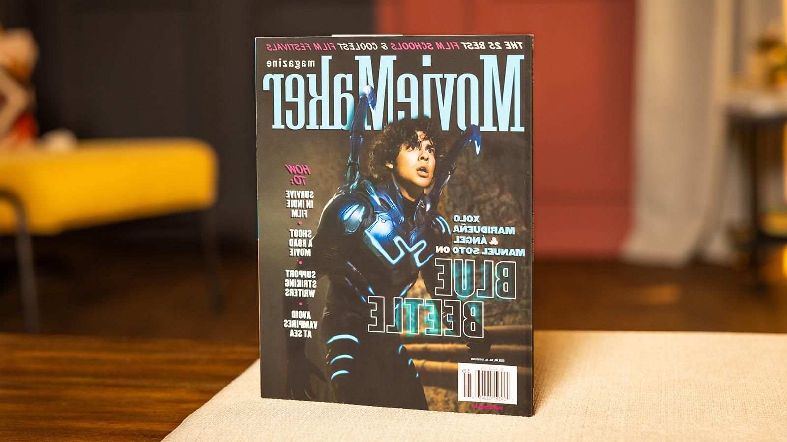 桌上放着一本《电影制作人》杂志. 封面上是一个穿着蓝色甲壳虫服装的演员. 标题是“25所最佳电影学院” & “最酷的电影节”横贯顶部.